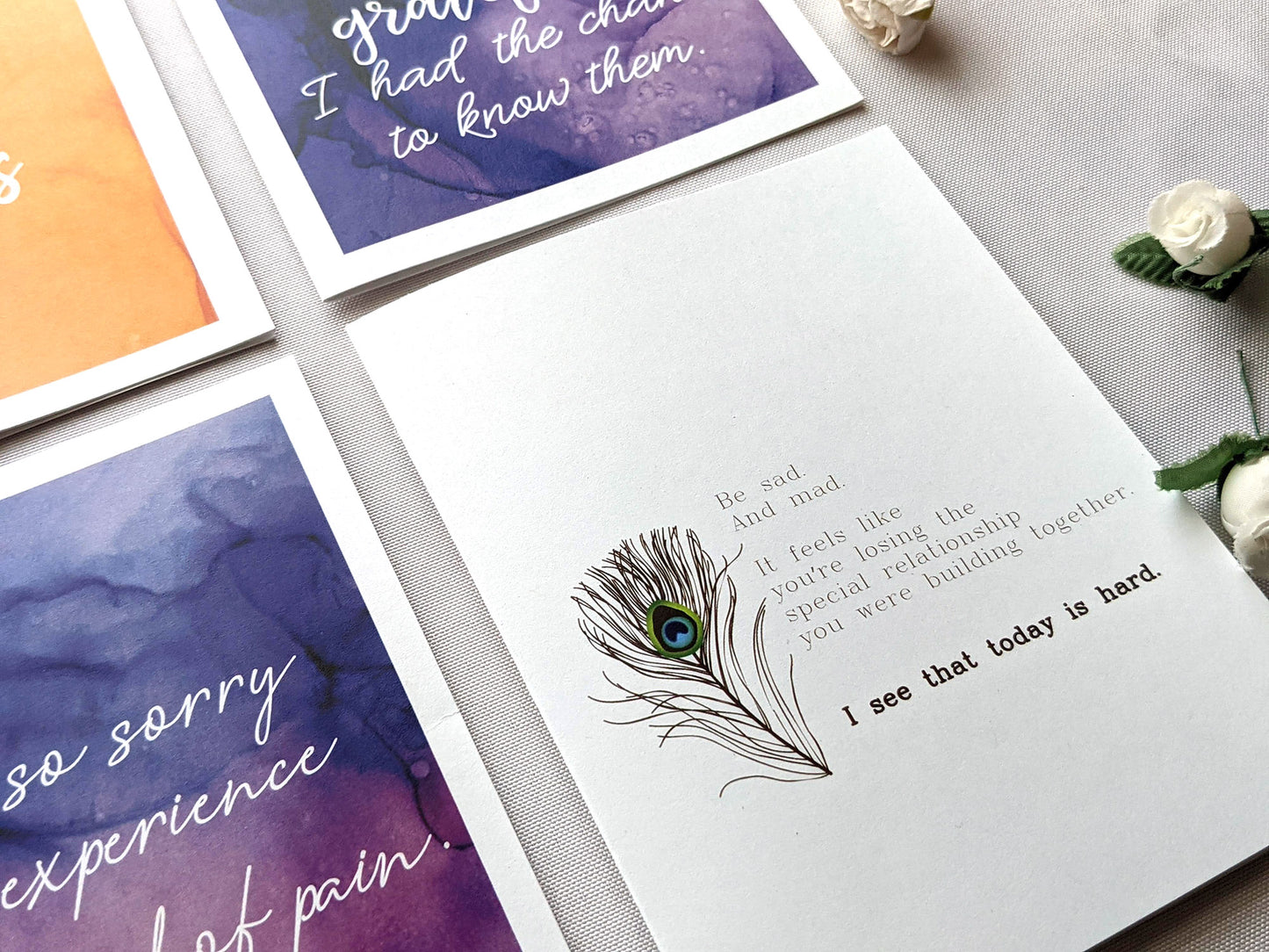 Angled view of greeting cards laying on a white background with faux flower buds.