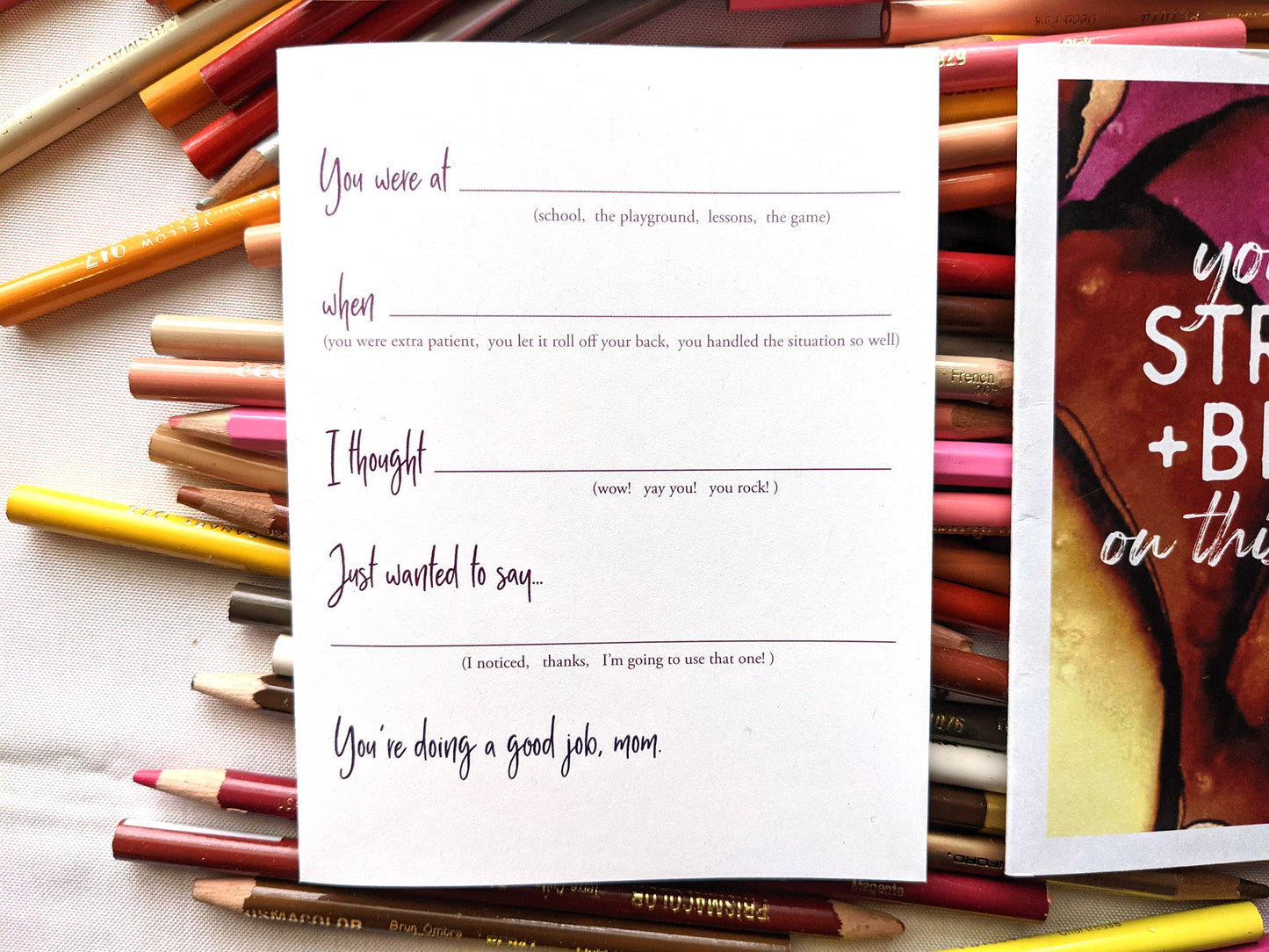 Two greeting cards laying on a pile of colored pencils.