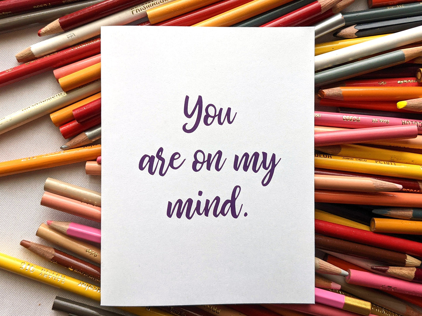 Greeting card laying on top of a pile of colored pencils.
