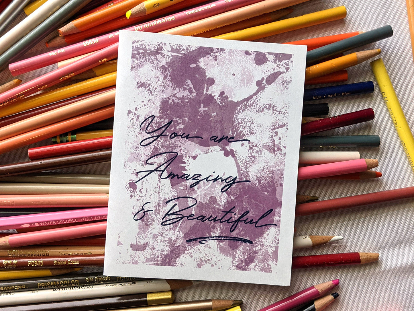 Greeting card laying on a pile of colored pencils.
