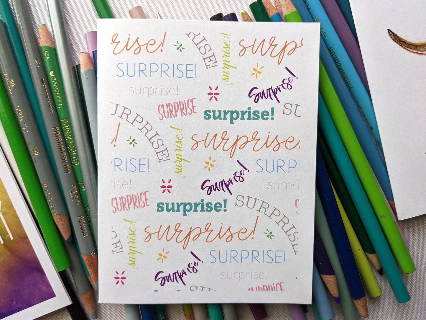 Greeting card laying on a pile of colored pencils.