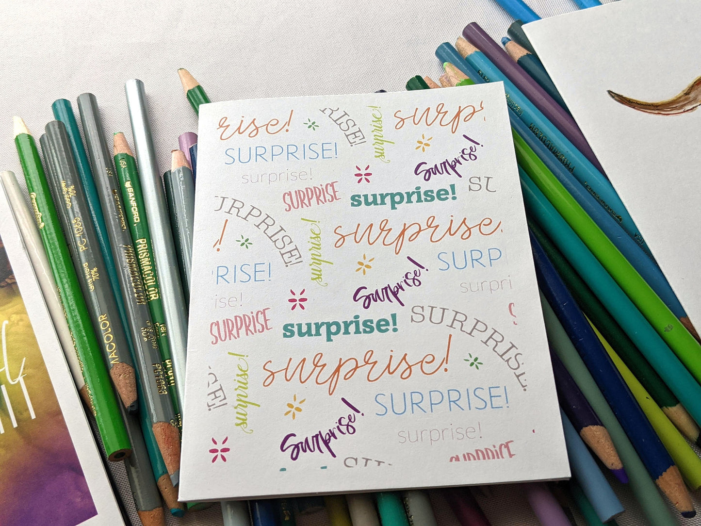 Greeting card laying on a pile of colored pencils.