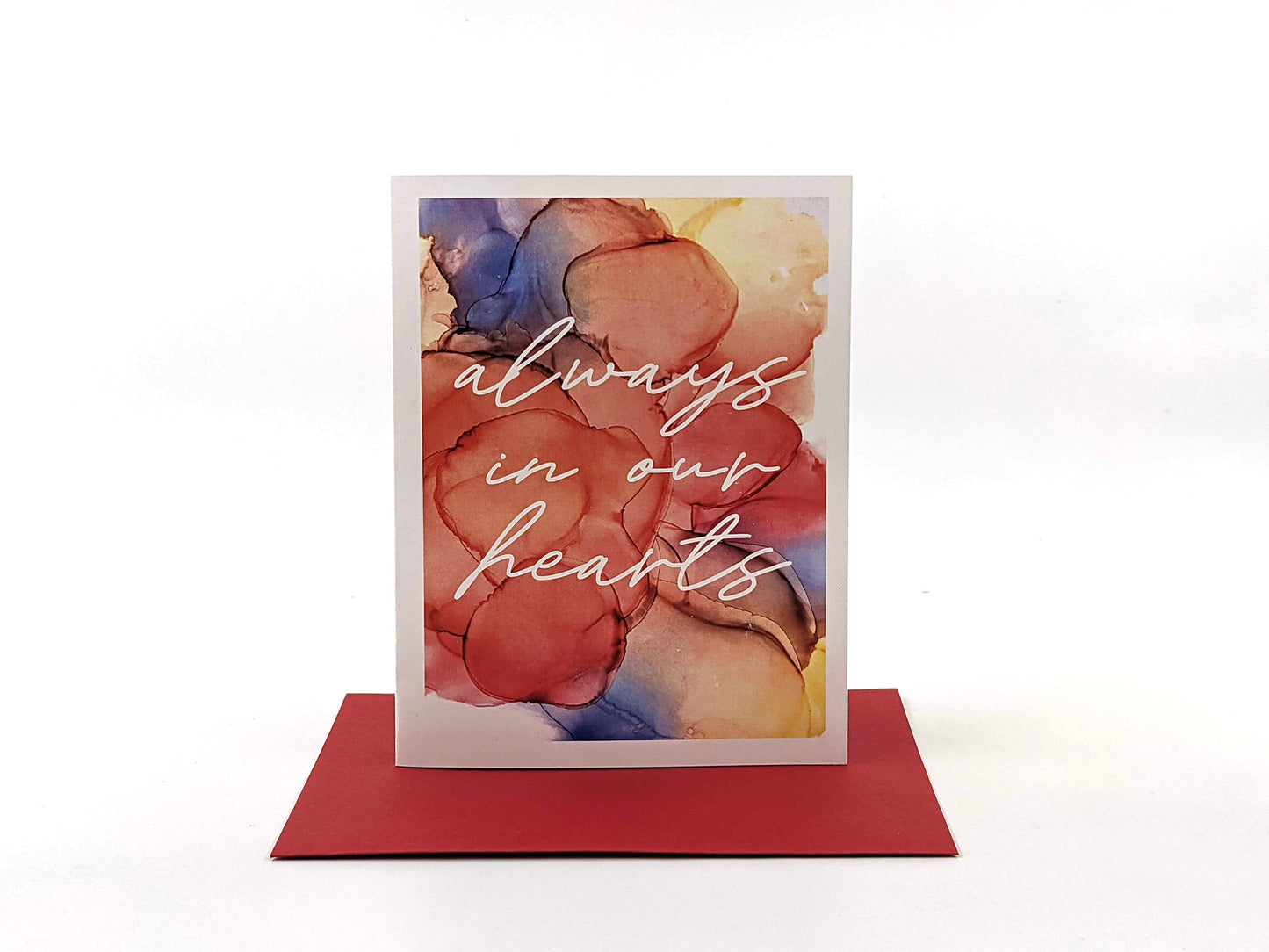 Greeting card standing upright on top of a colorful envelope against a white background.