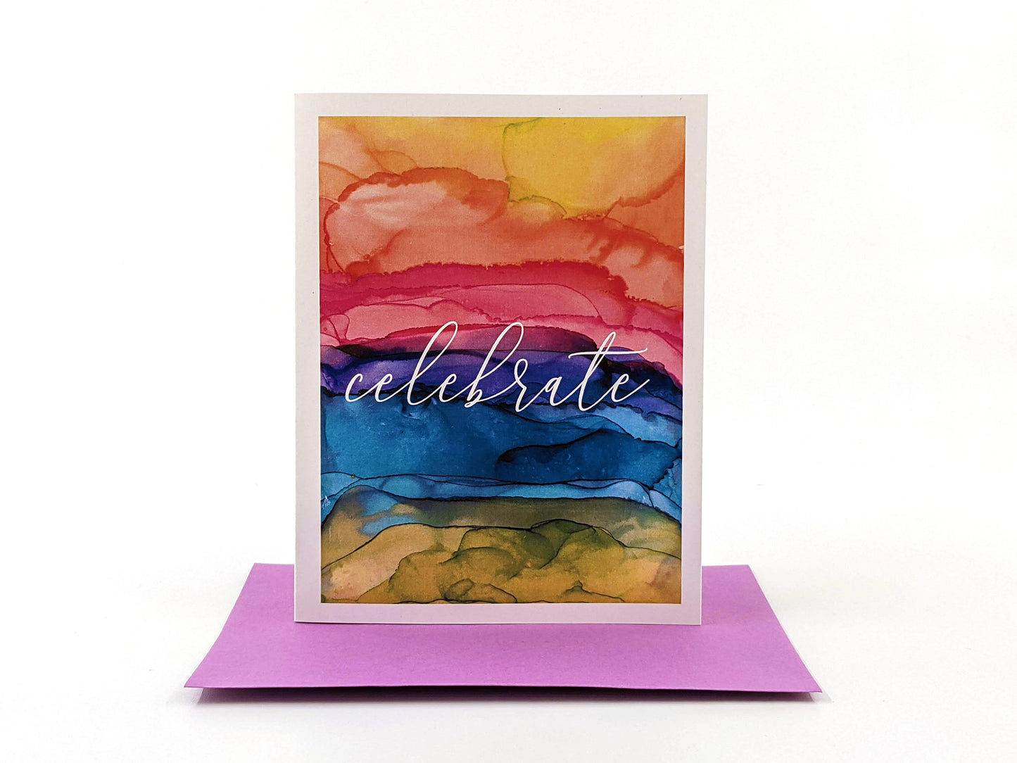 Greeting card standing upright on top of a colorful envelope against a white background.