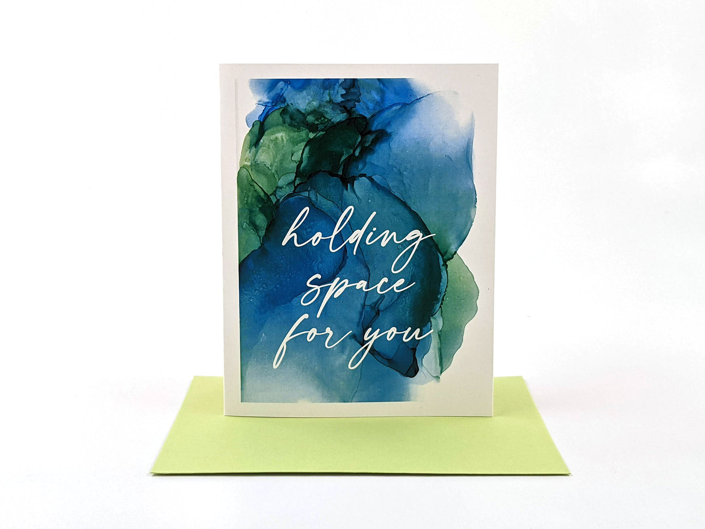 Greeting card standing upright on top of a colorful envelope against a white background.