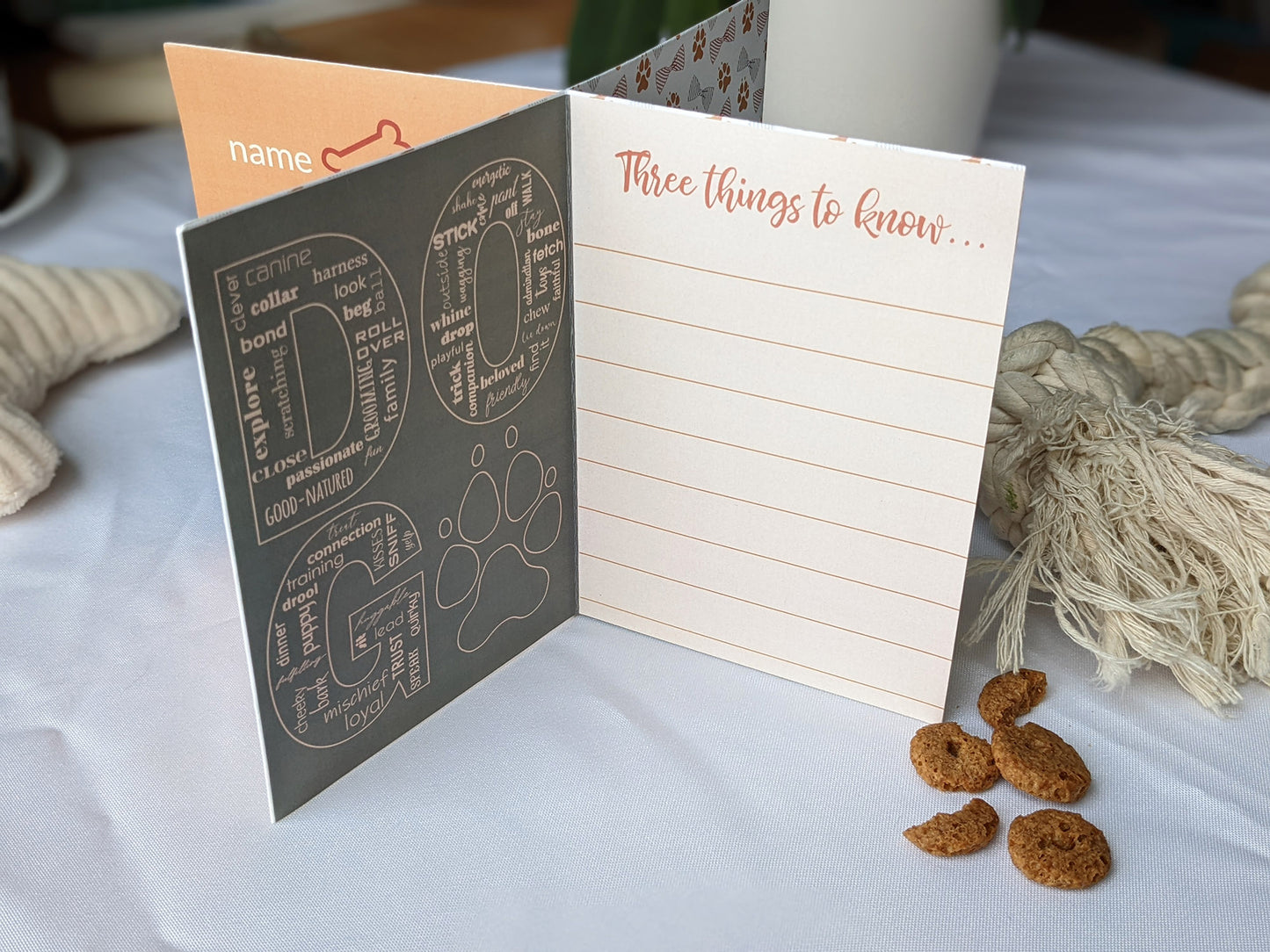 Lifestyle photo of centerpiece with dog toys and treats surrounding it showing the wording on the panels.