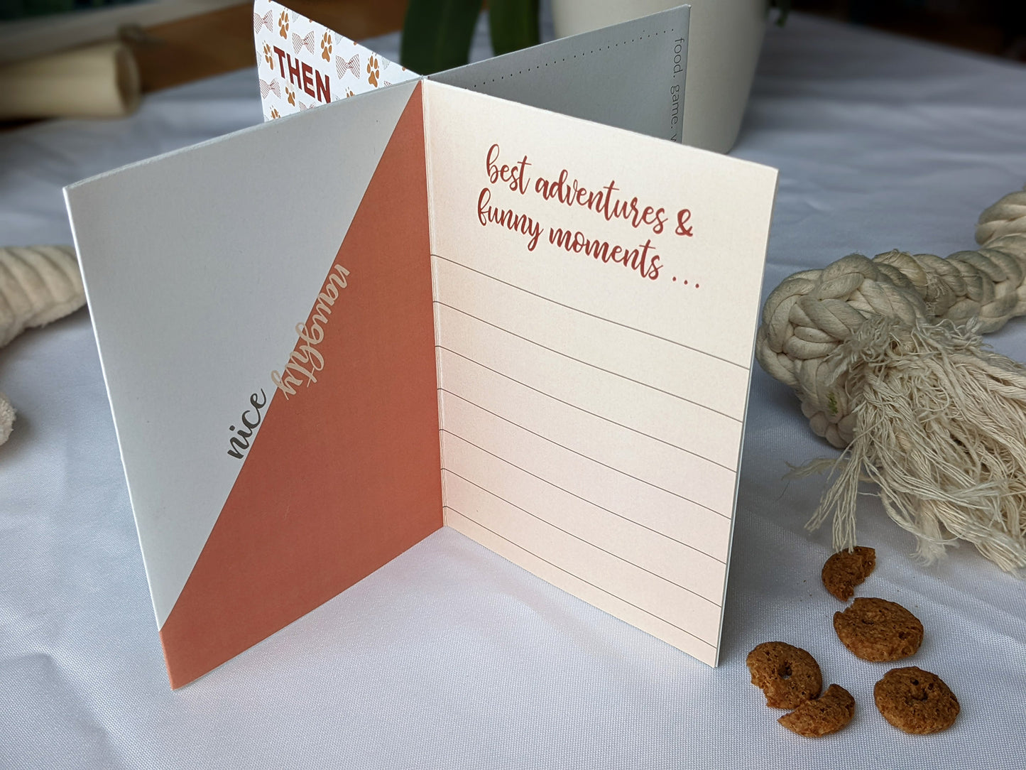 Lifestyle photo of centerpiece with dog toys and treats surrounding it showing the wording on the panels.