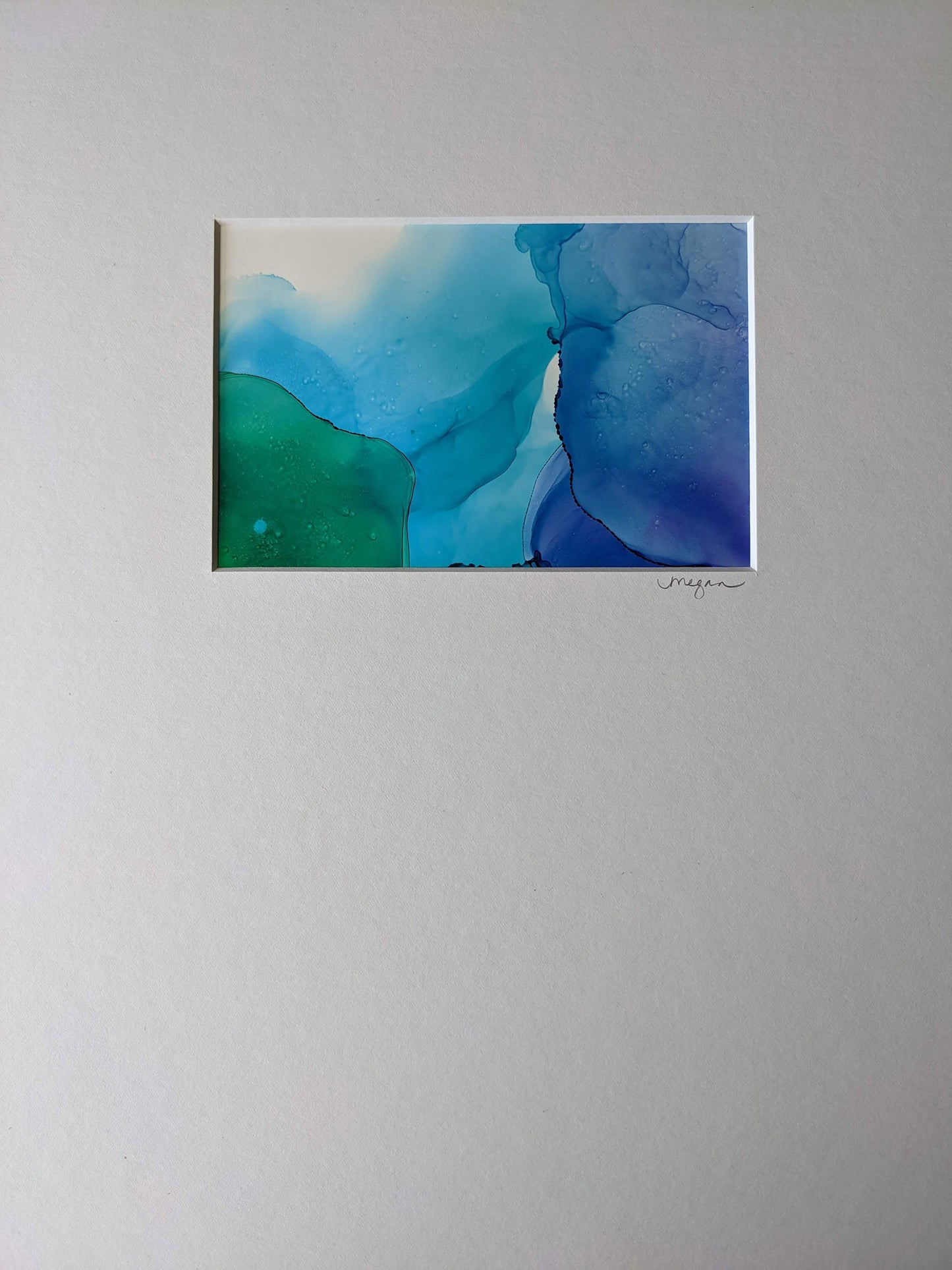 Zoomed in view of three paintings framed in black hung on a grey wall.