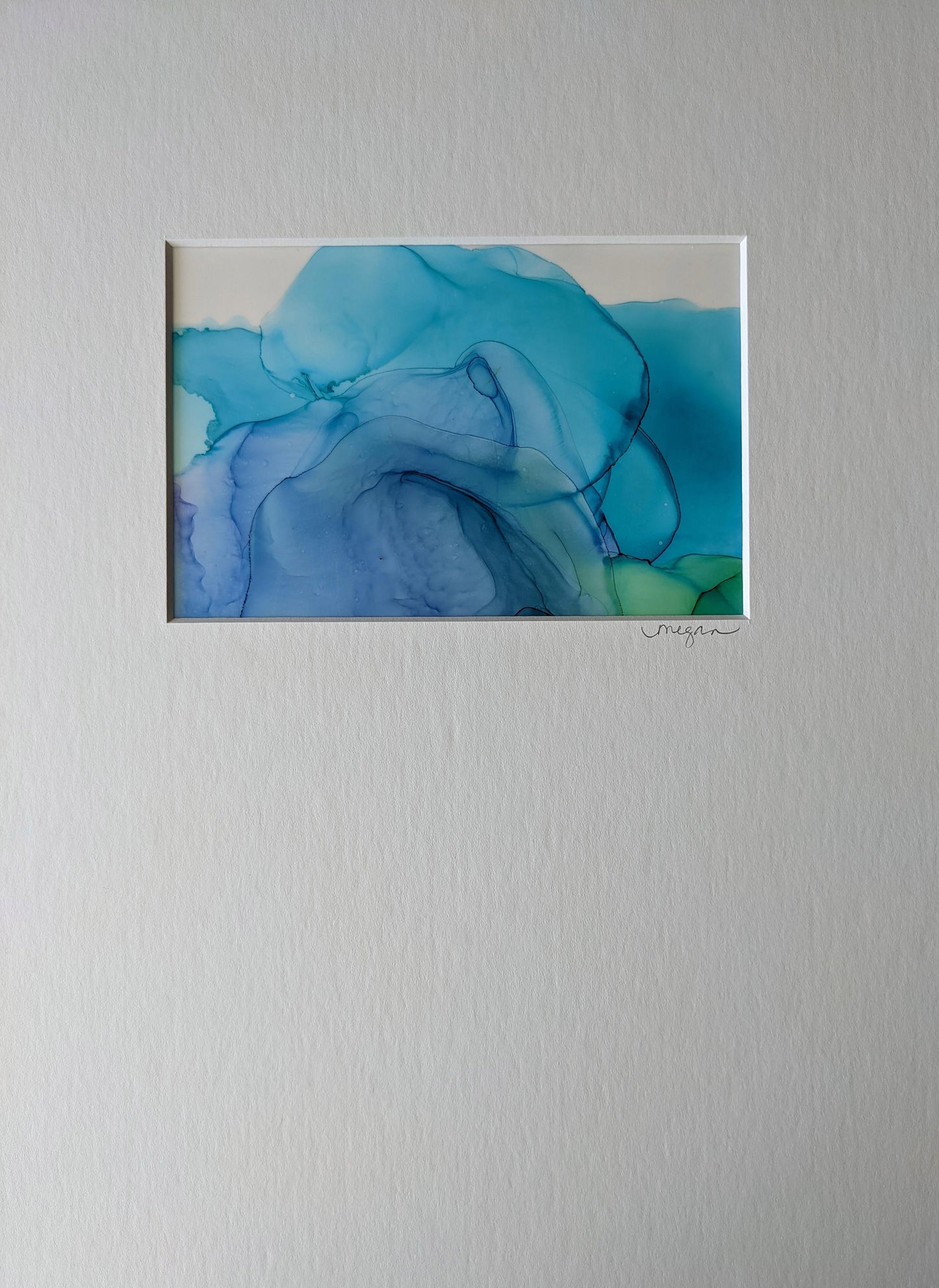 Zoomed in view of three paintings framed in black hung on a grey wall.