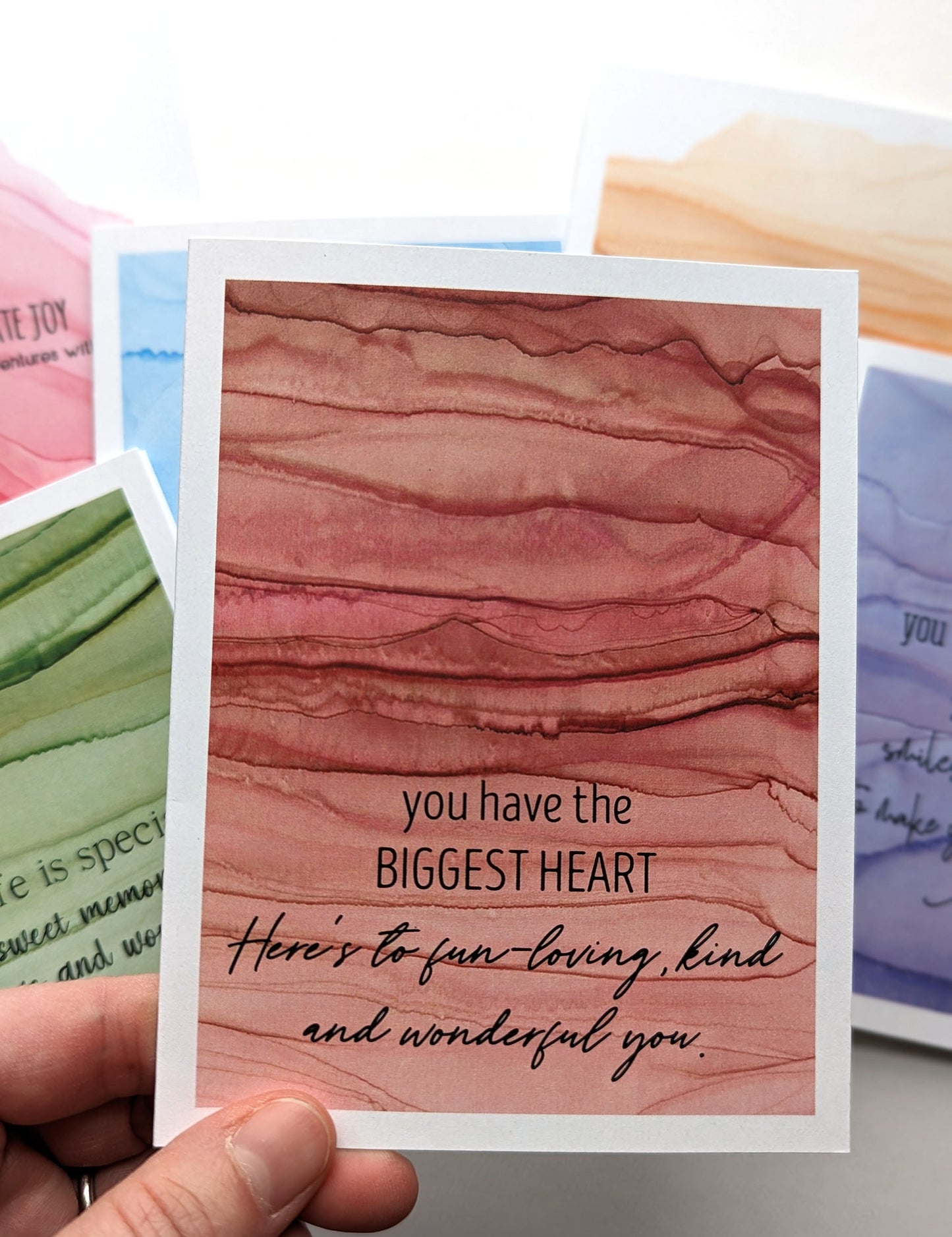 Hand holding the greeting card above the stack of others in the collection.