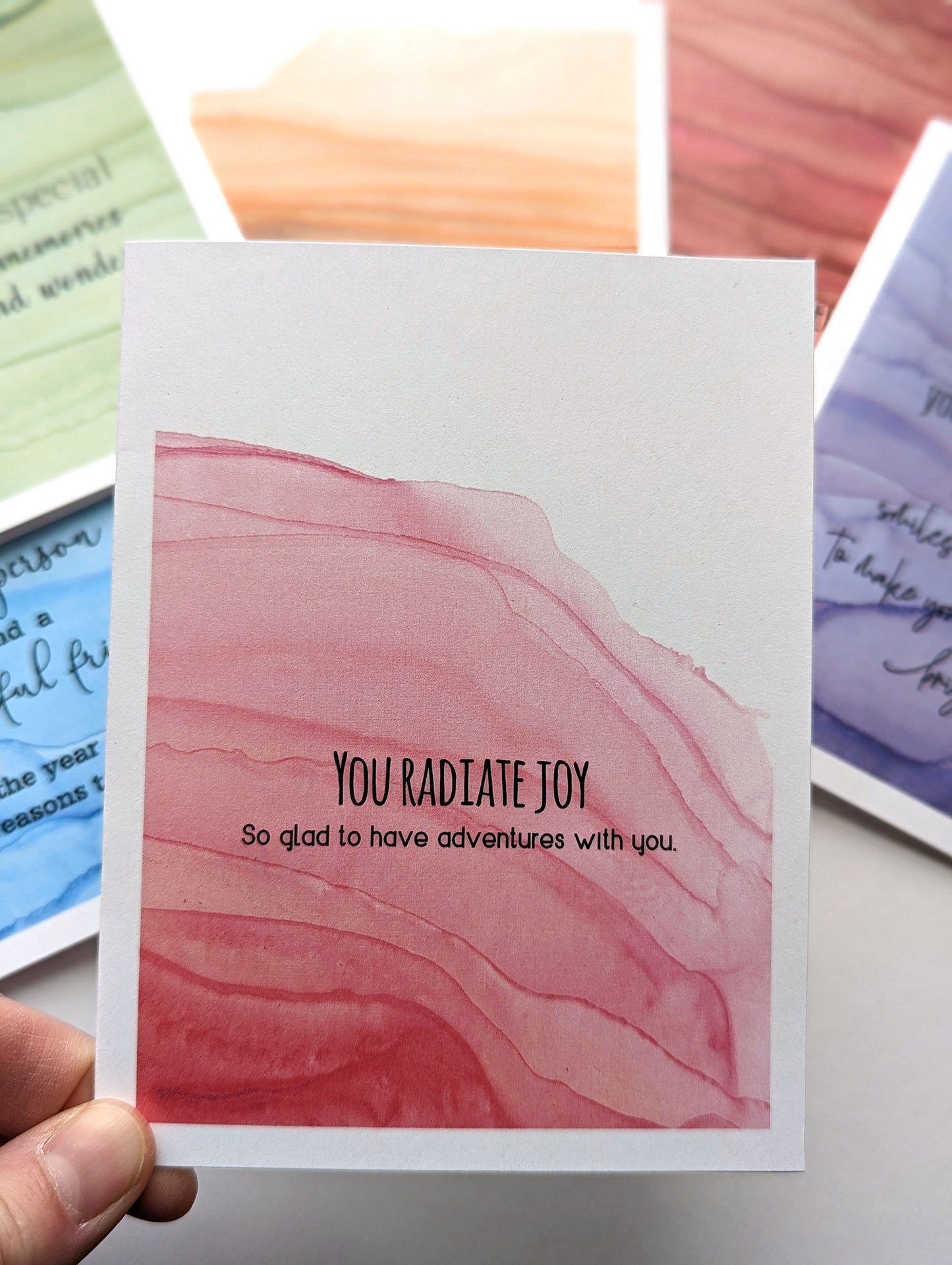 Hand holding the greeting card above the stack of others in the collection.