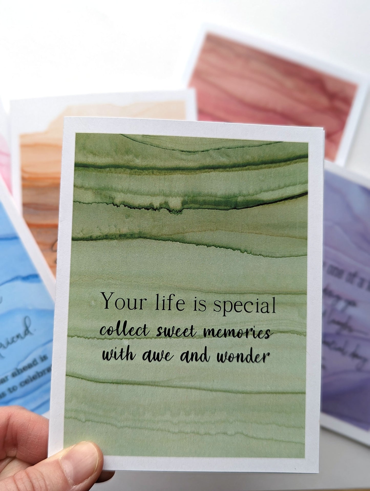 Hand holding the greeting card above the stack of others in the collection.
