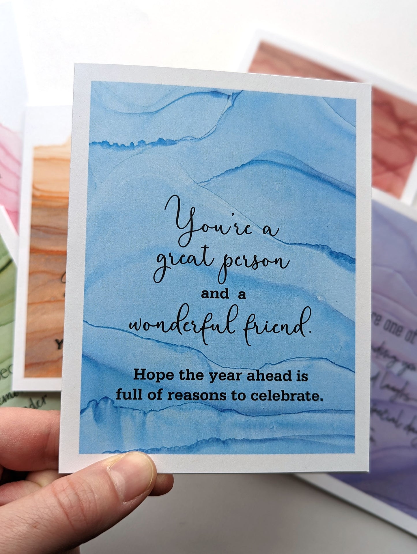 Hand holding the greeting card above the stack of others in the collection.