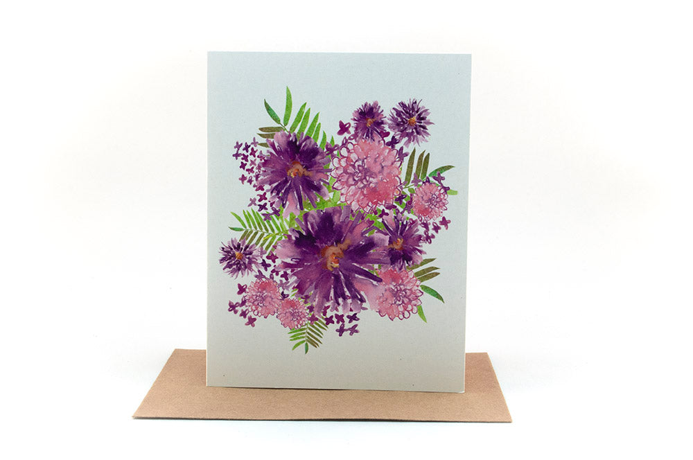 Greeting card standing upright on top of a colorful envelope against a white background.