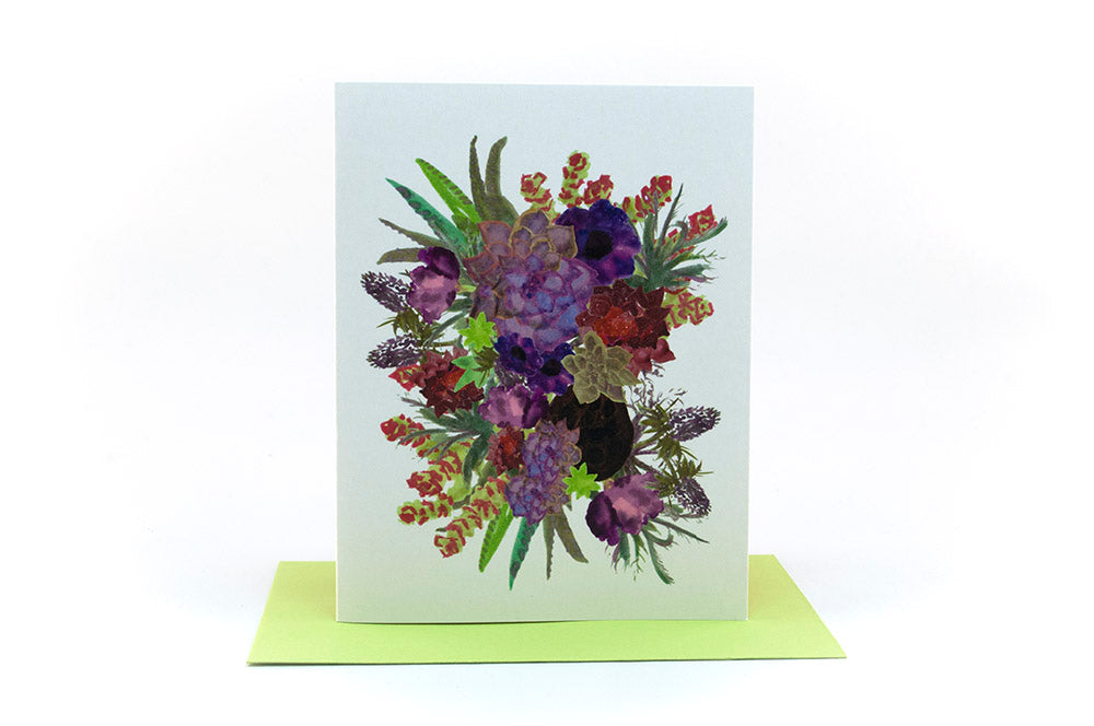 Greeting cards in a kraft box standing upright on top of a colored envelope against a white background.