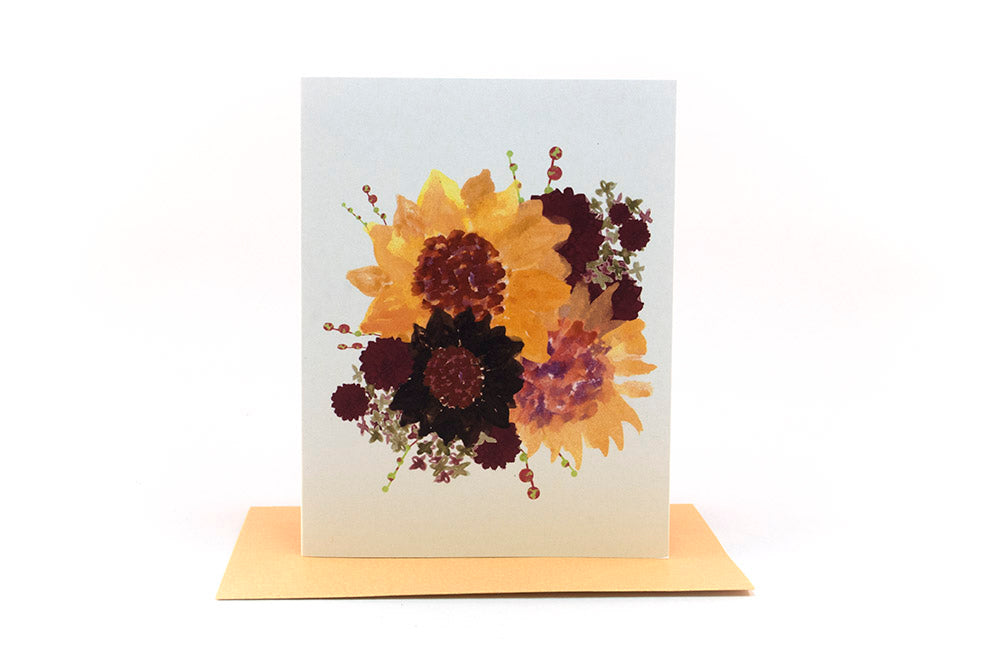 Greeting card standing upright on top of a colorful envelope against a white background.