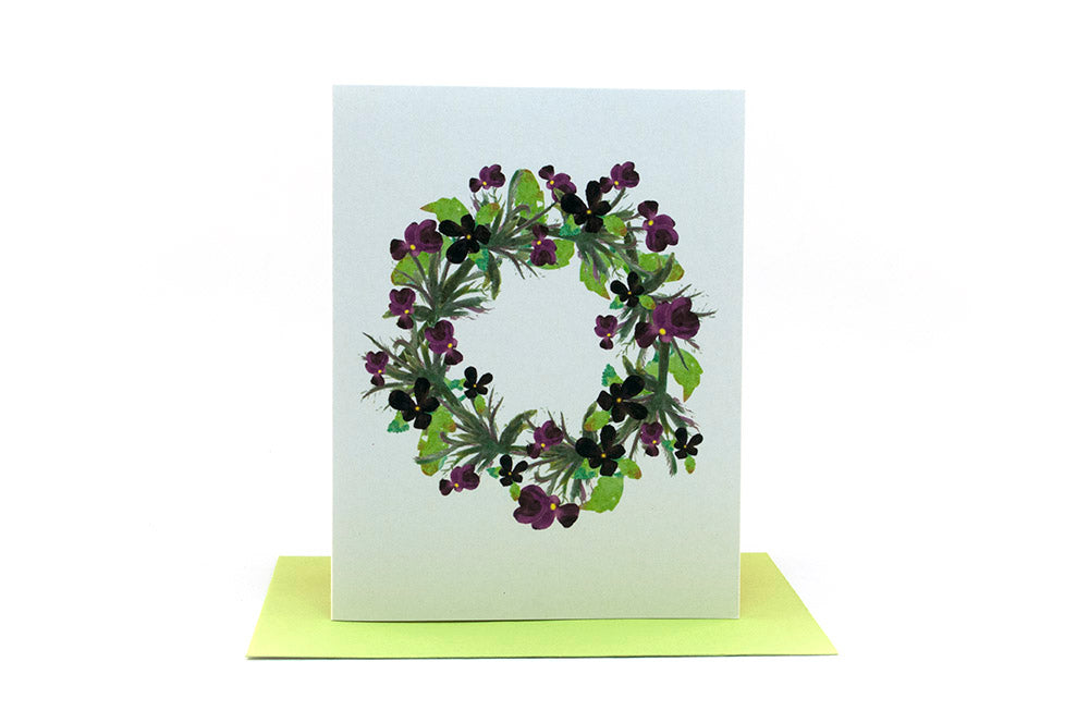 Greeting card standing upright on top of a colorful envelope against a white background.