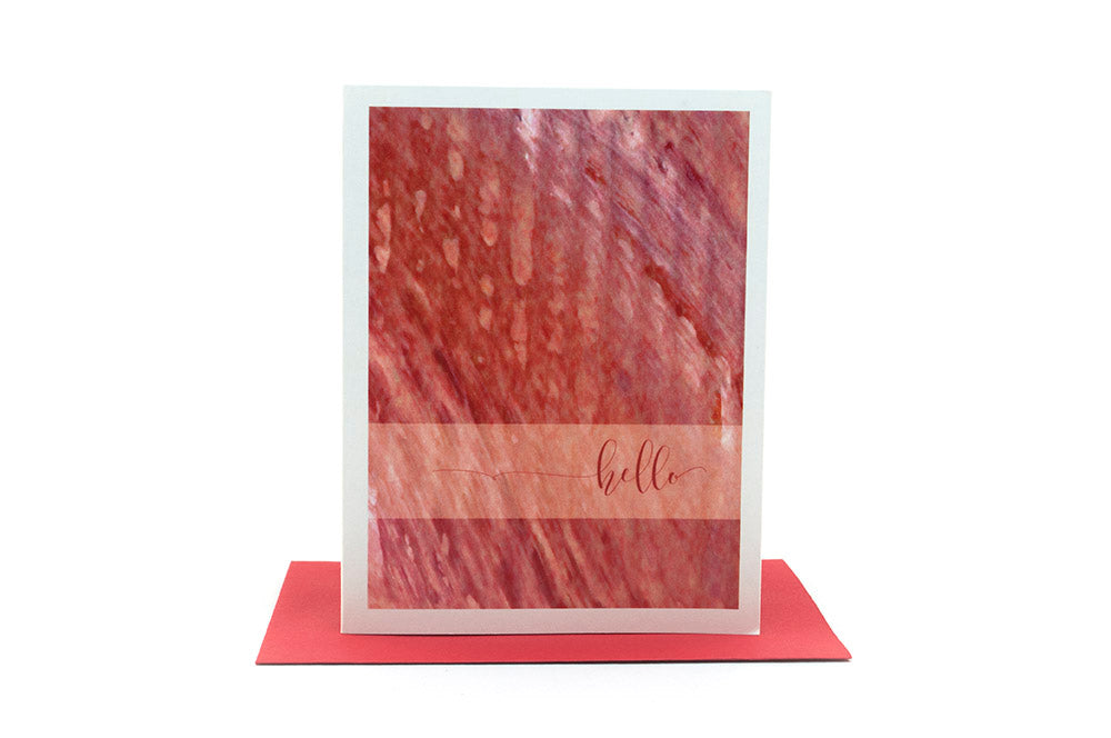 Greeting card standing upright on top of a colorful envelope against a white background.
