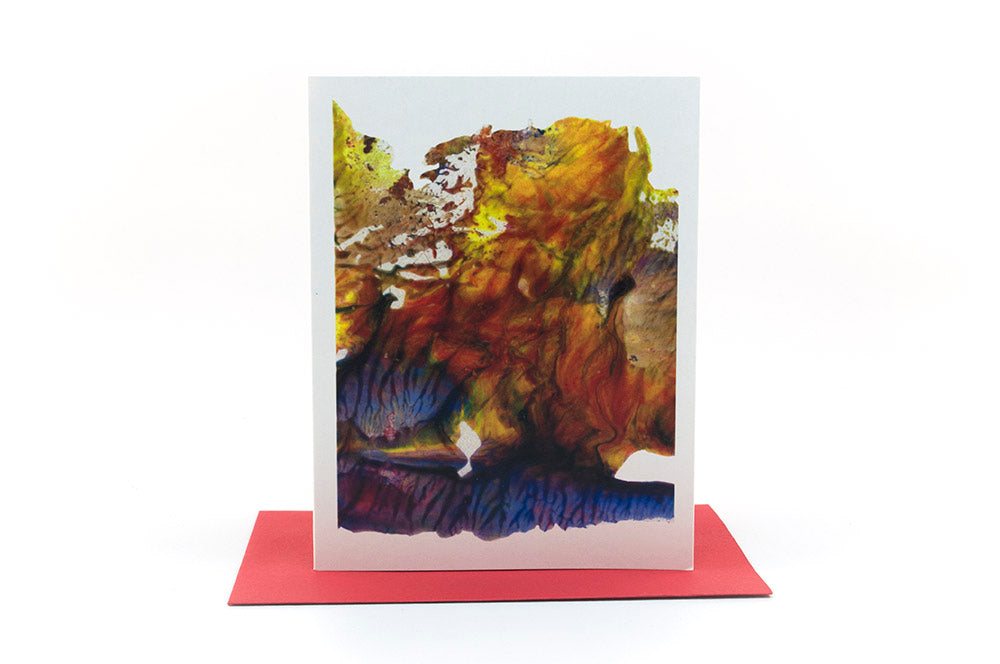 Greeting card standing upright on top of a colorful envelope against a white background.