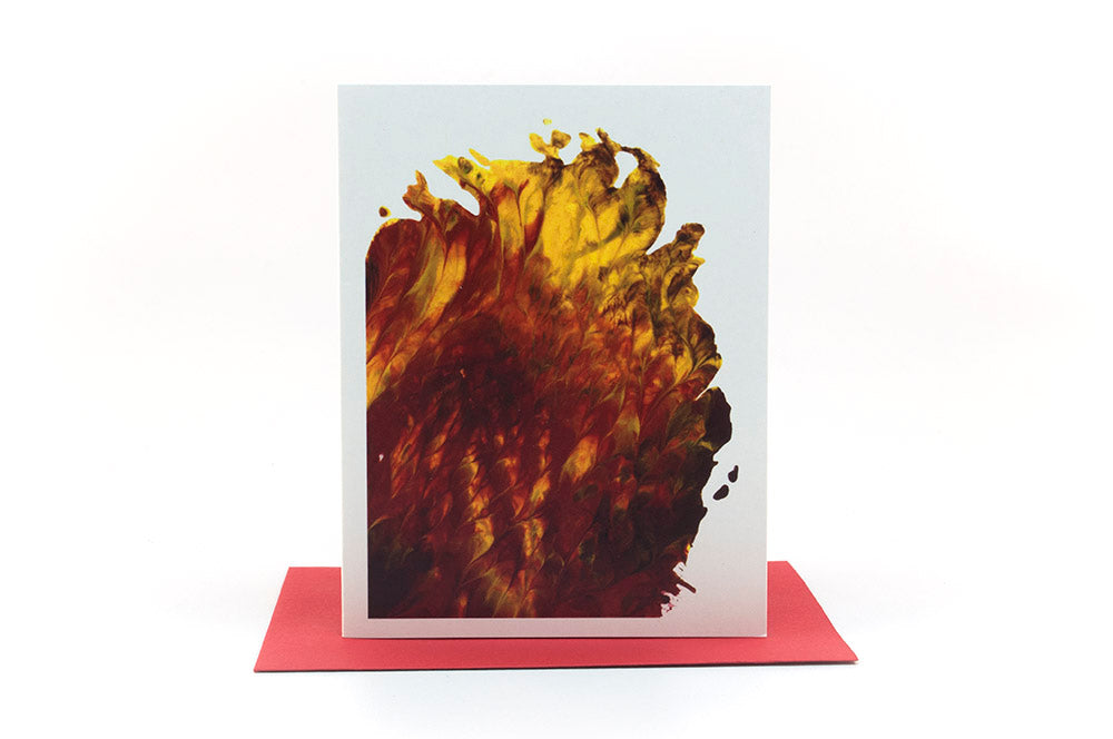 Greeting card showing an abstract painting in reds, yellows, and browns created from squishing acrylic paint between pieces of cardboard. It sits on a red envelope .