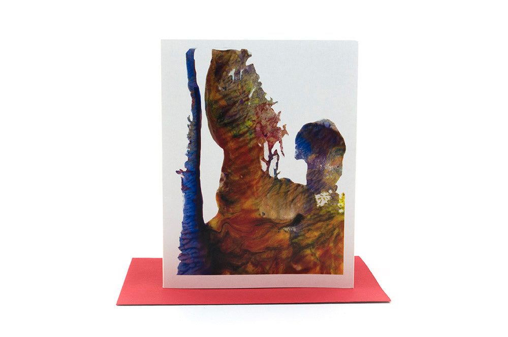 Greeting card standing upright on top of a colorful envelope against a white background.