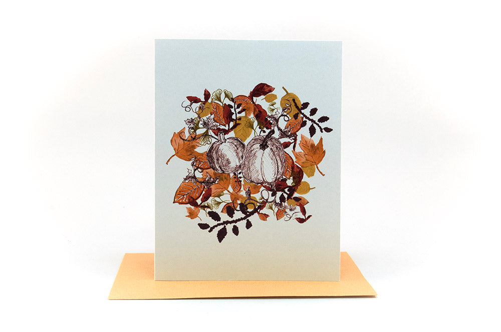 Greeting card standing upright on top of a colorful envelope against a white background.