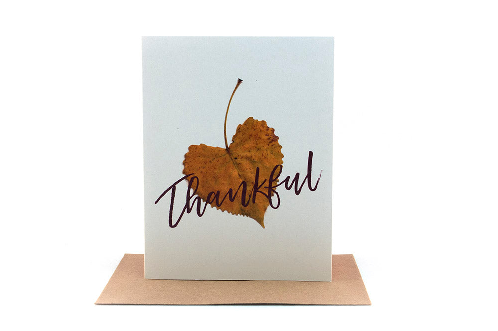 Greeting card standing upright on top of a kraft envelope against a white background.