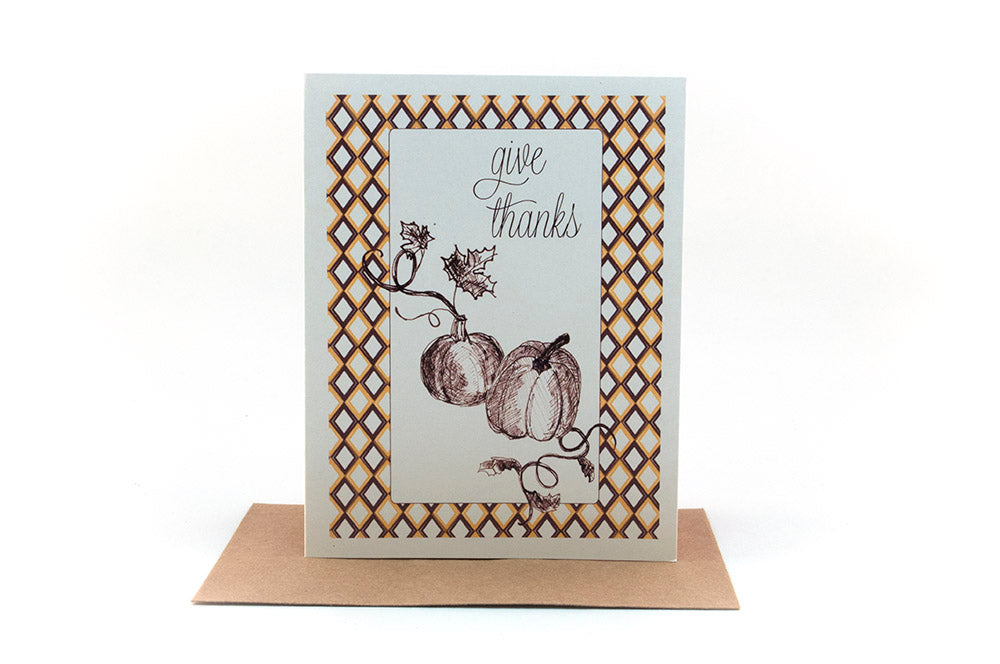 Greeting card, seen from above, with a kraft, square flap envelope, pencils, pencil sharpener and shavings on a white background.
