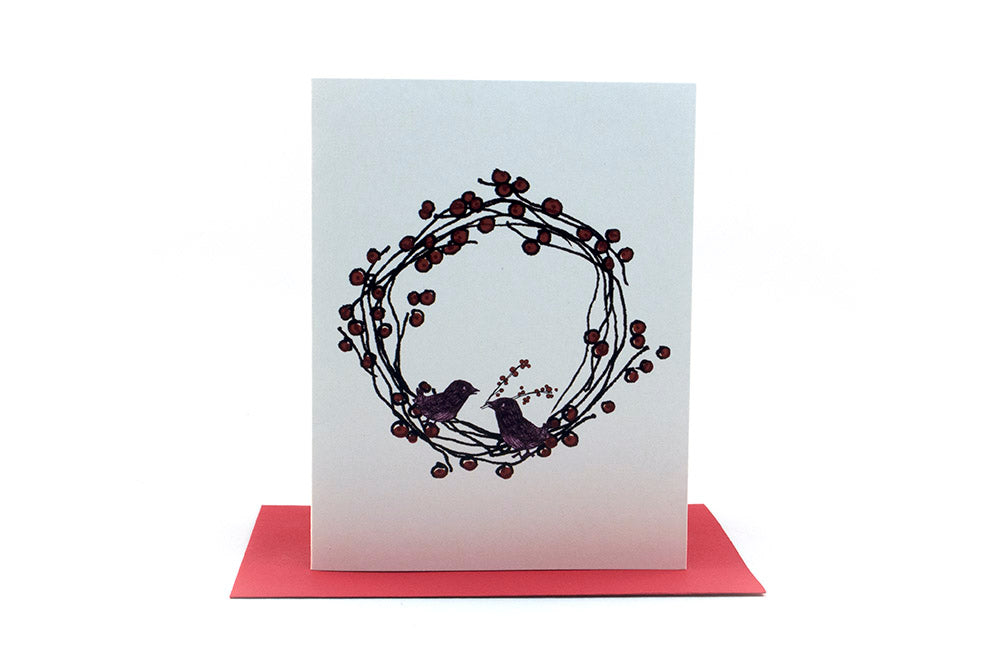 Greeting card standing upright on top of a colorful envelope against a white background.