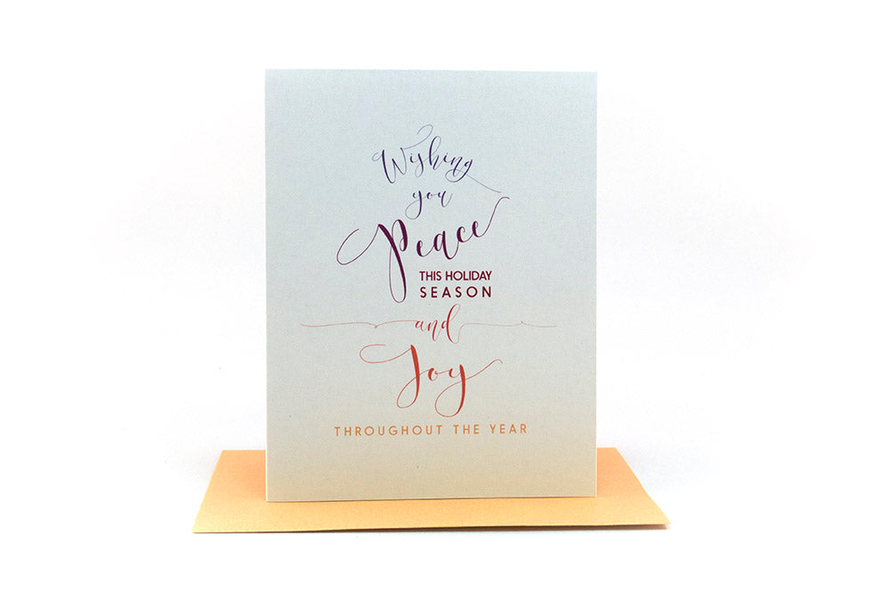 Greeting card standing upright on top of a colorful envelope against a white background.