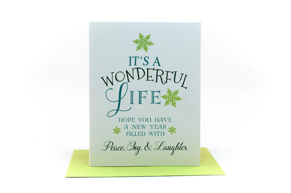 Greeting card standing upright on top of a colorful envelope against a white background.