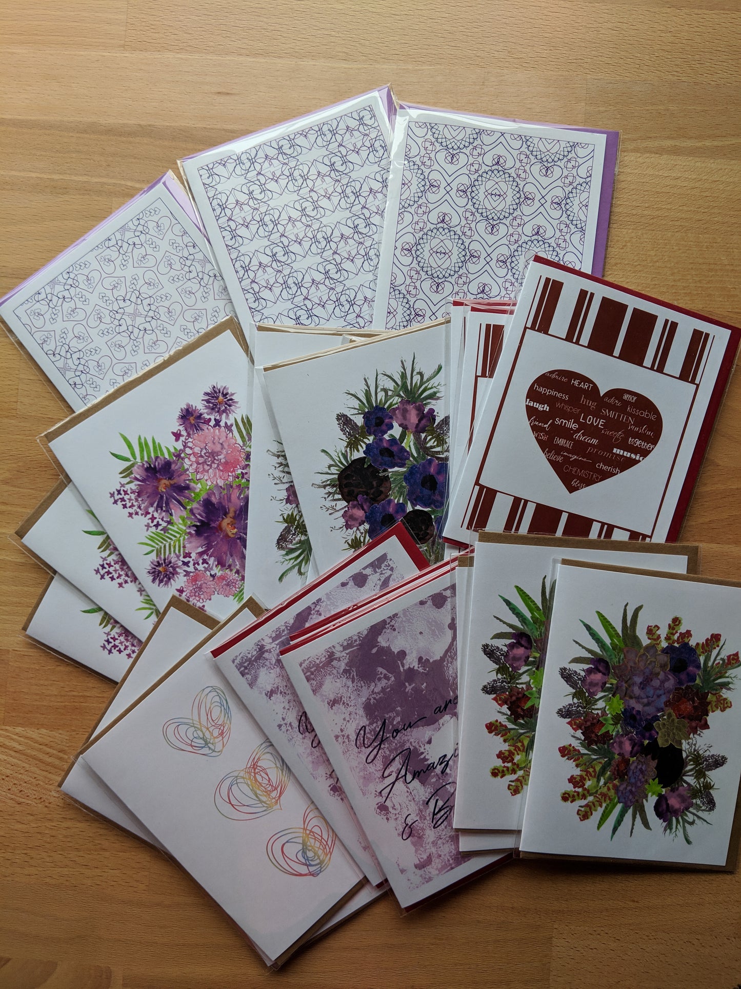 Many packaged greeting cards overlapping on a wooden table.