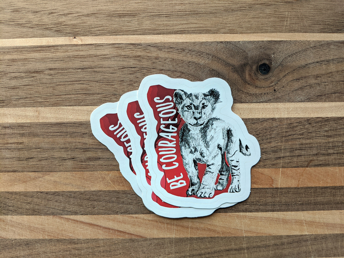 Three stickers overlapping on a wooden surface.
