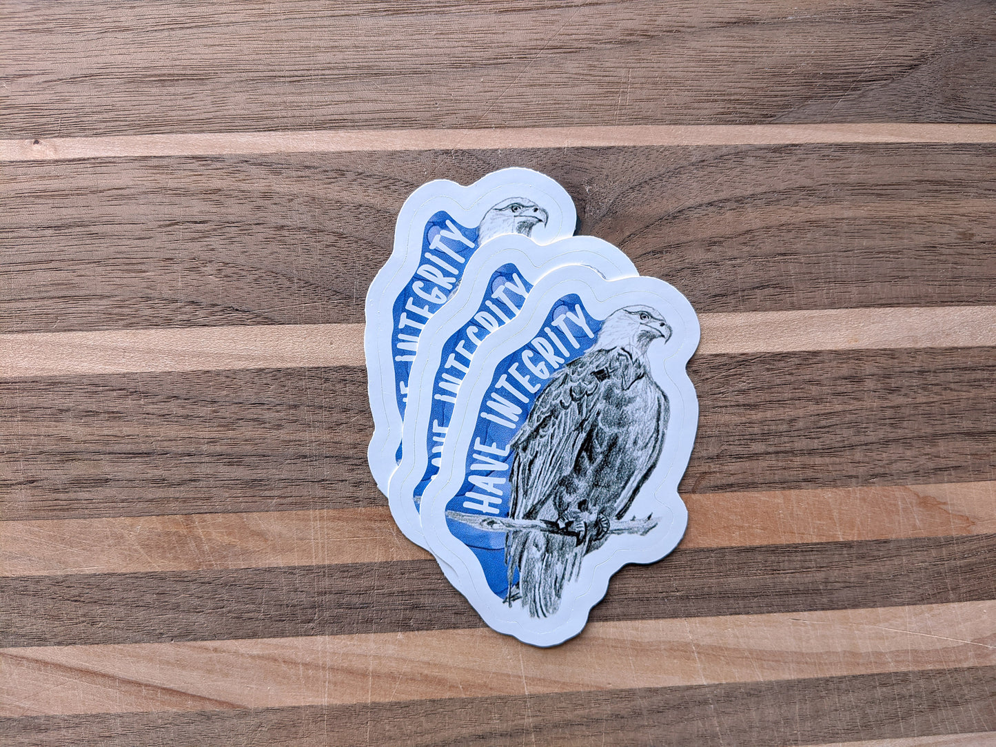 Three stickers overlapping on a wooden surface.