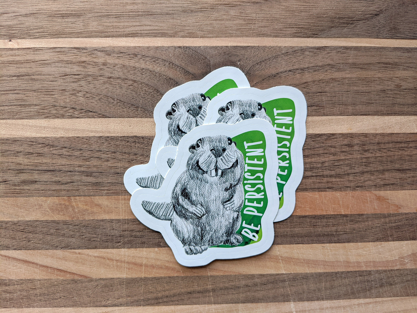 Three stickers overlapping on a wooden surface.