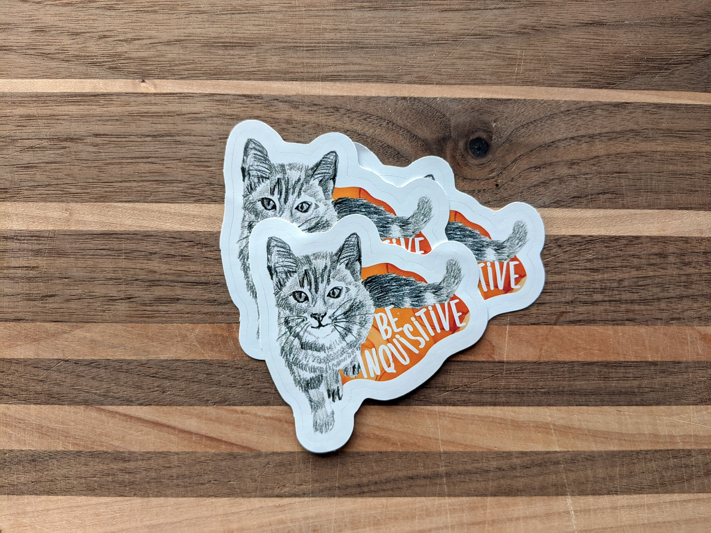 Three stickers overlapping on a wooden surface.