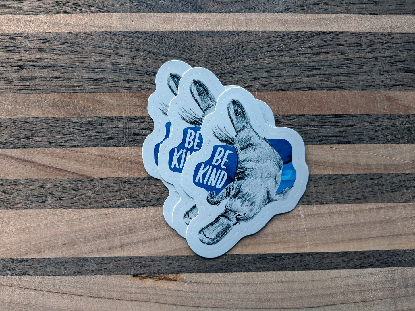 Three stickers overlapping on a wooden surface.