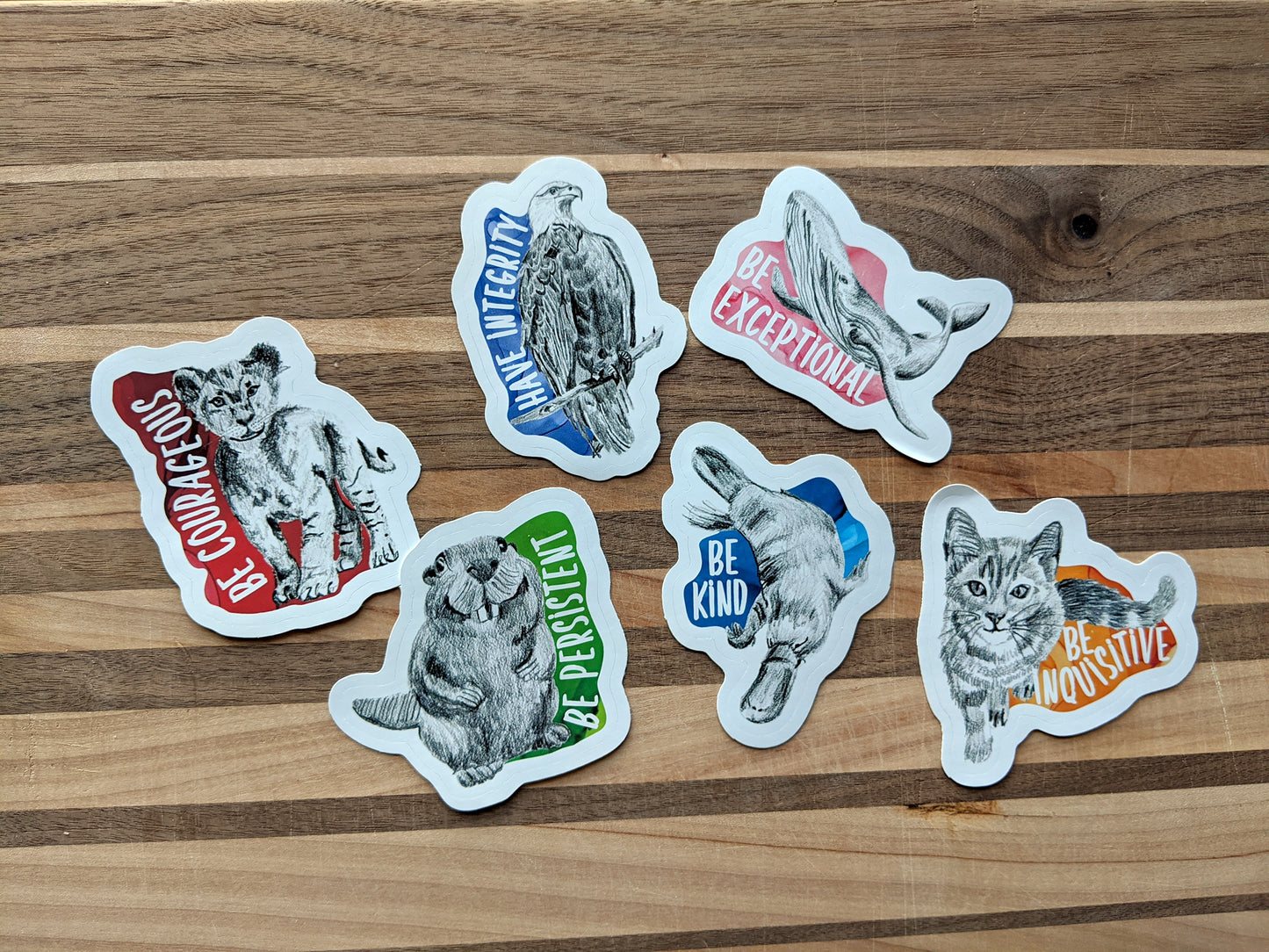 Six stickers laying on a wooden surface.