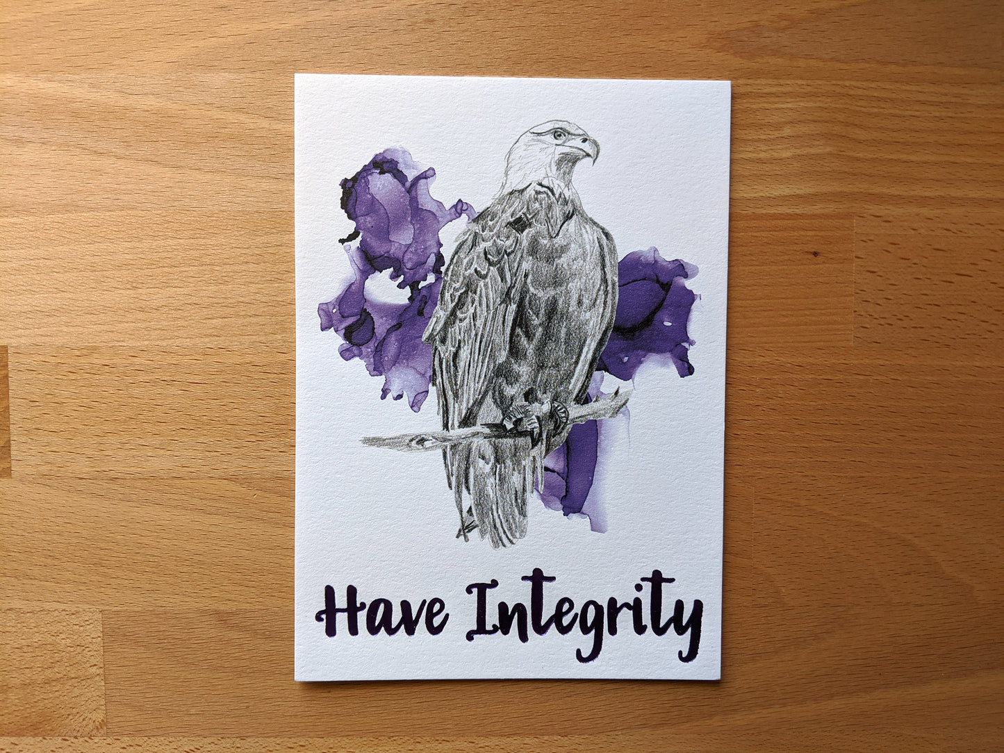 Art print accented in foil laying on a wooden tabletop.