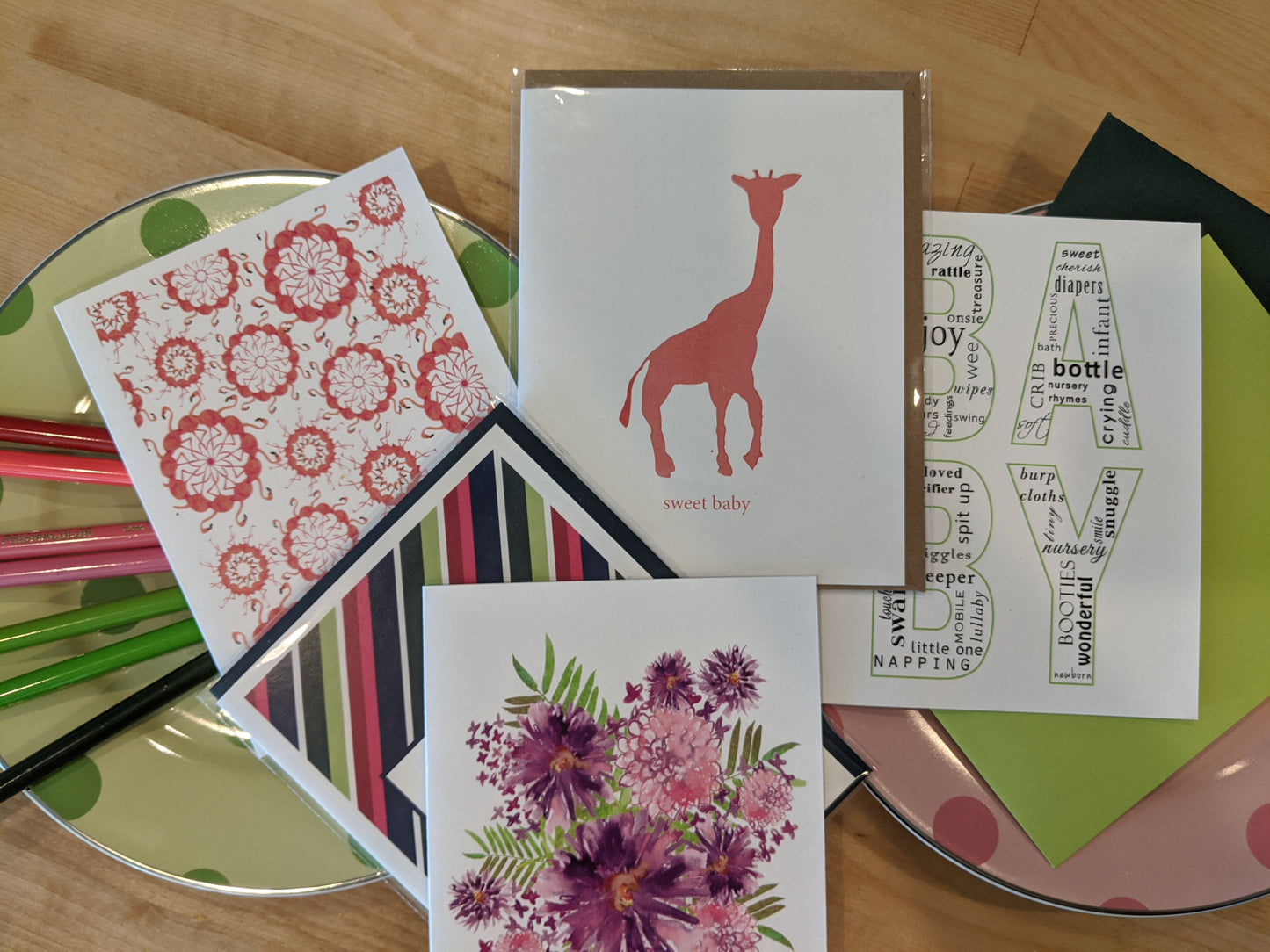 Five greeting cards overlapping on polka dot appetizer plates on a wooden table top.