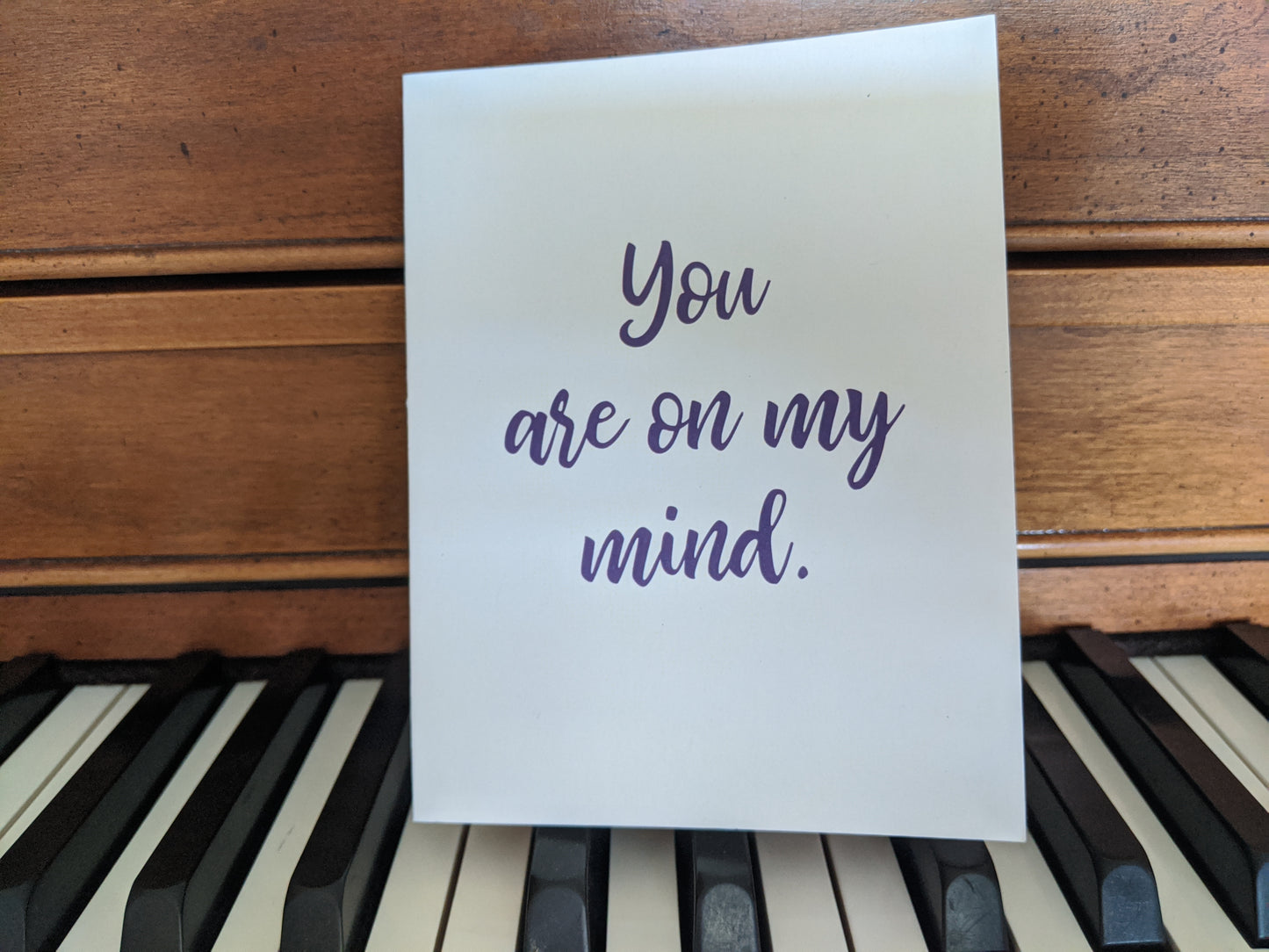 Greeting card leaning on the keyboard of a piano.