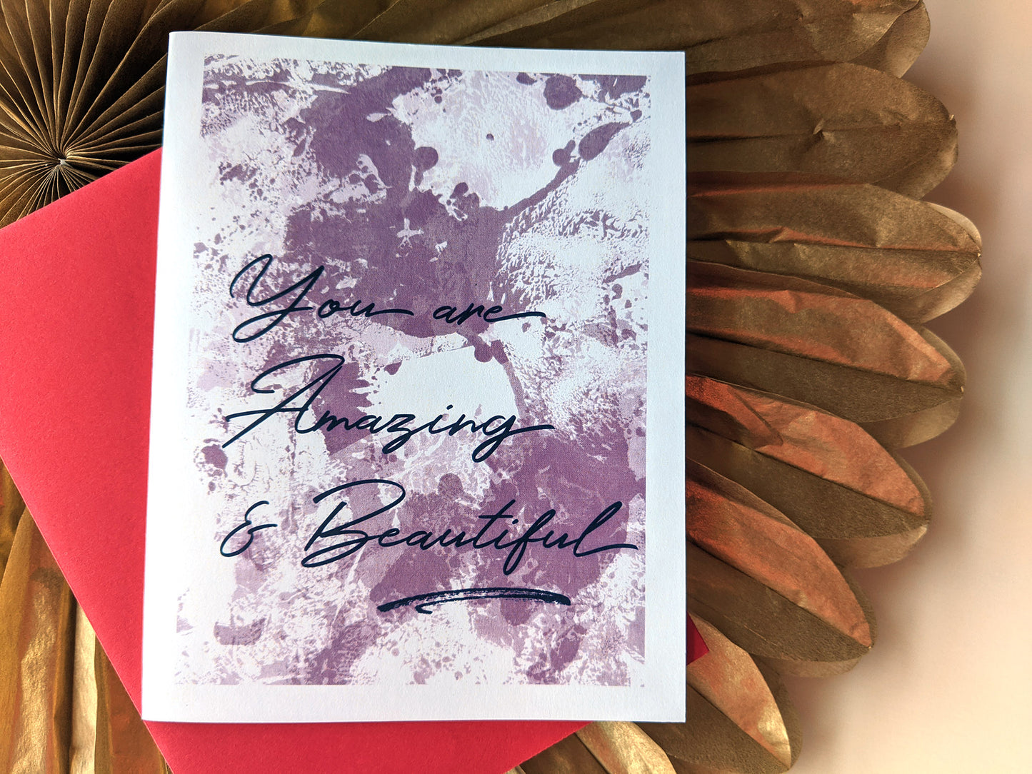 Greeting card and colorful envelope laying on a gold paper medallion.
