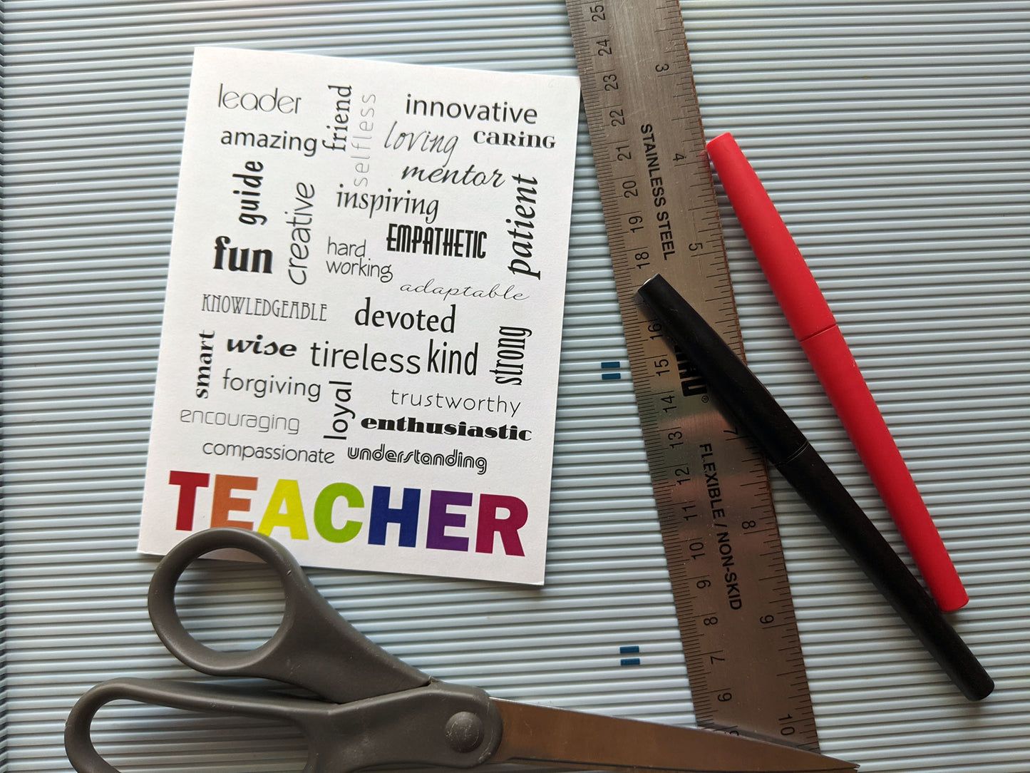 Greeting card laying on a ridged light blue surface with scissors, ruler, and felt tipped pens.
