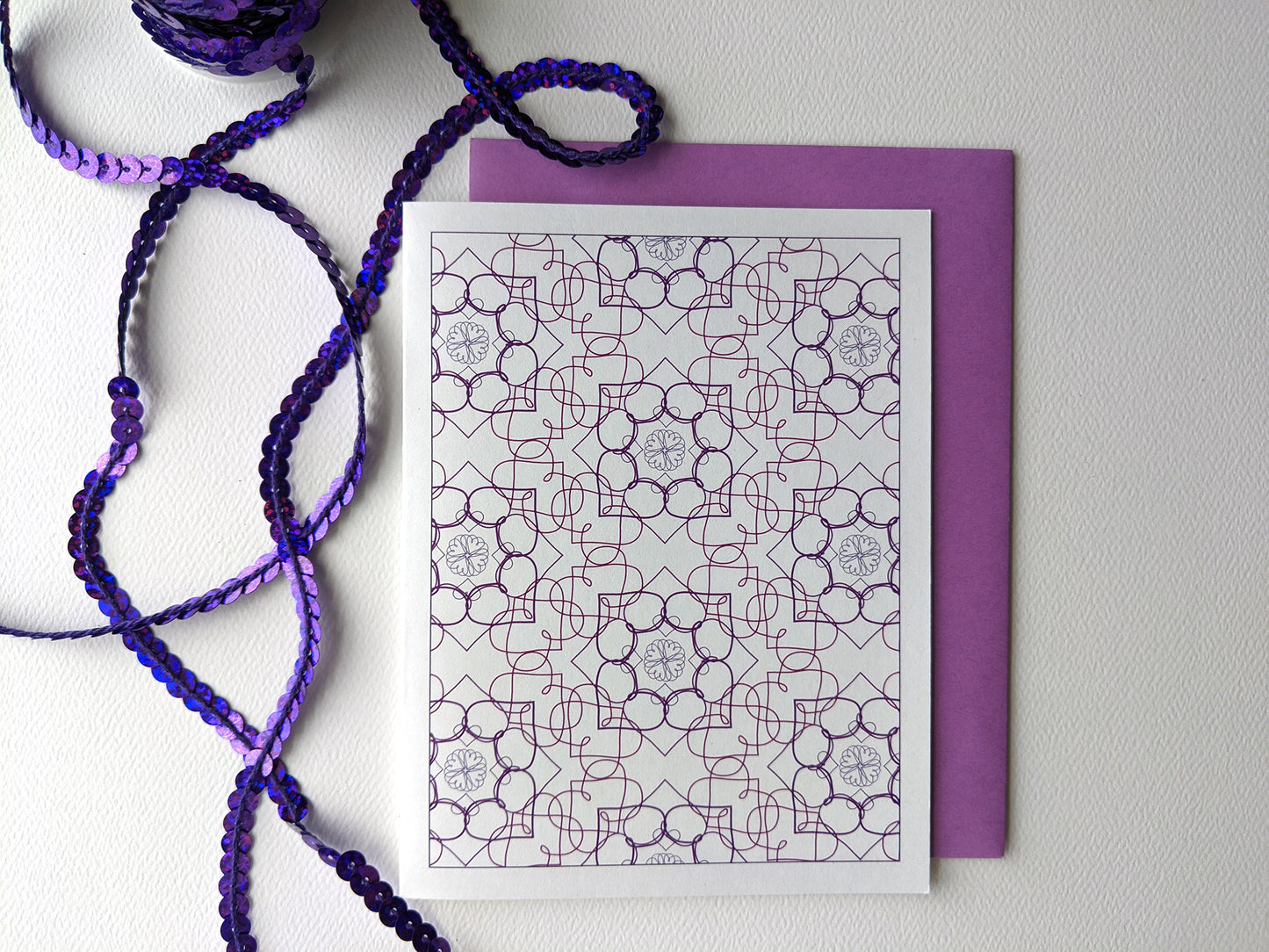 Greeting card with colorful envelope on a white background with purple sequins.