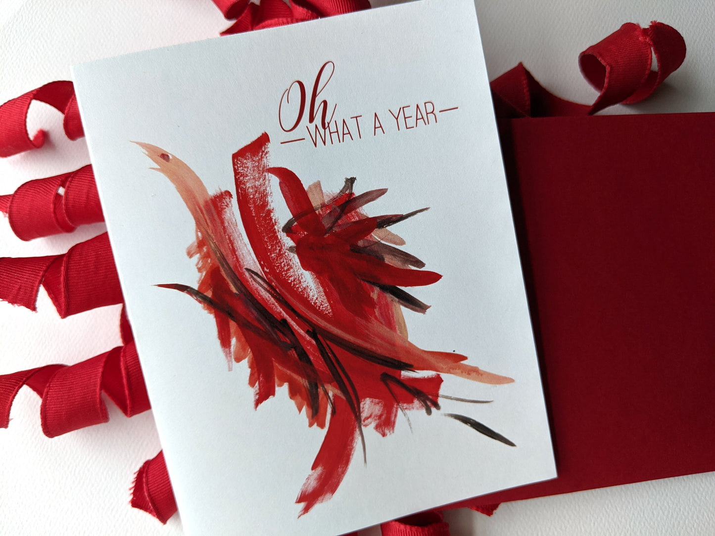 Greeting card with a colorful envelope on a white background with curly red fabric ribbon.