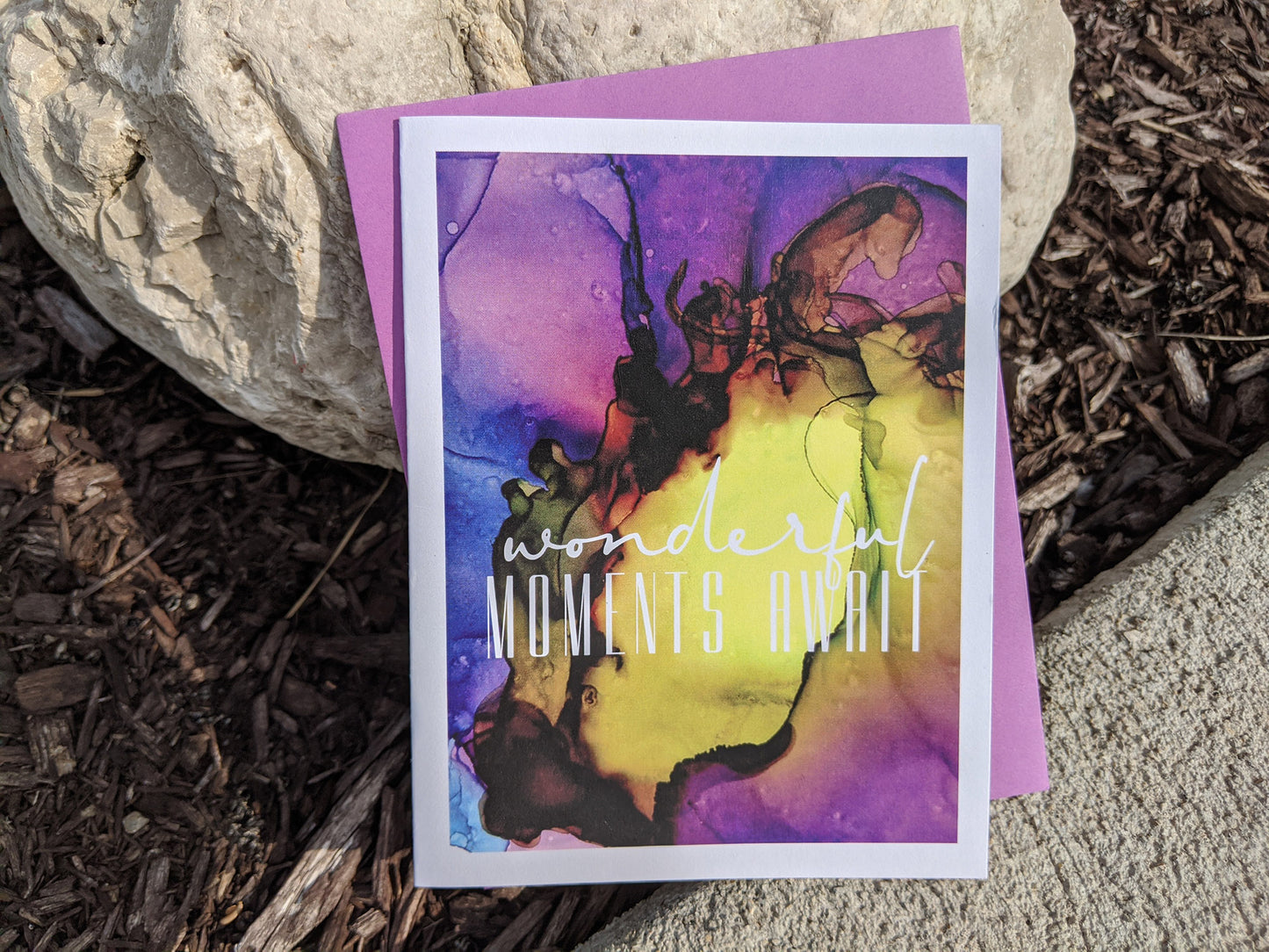 Greeting card laying on rocks with colorful envelope.