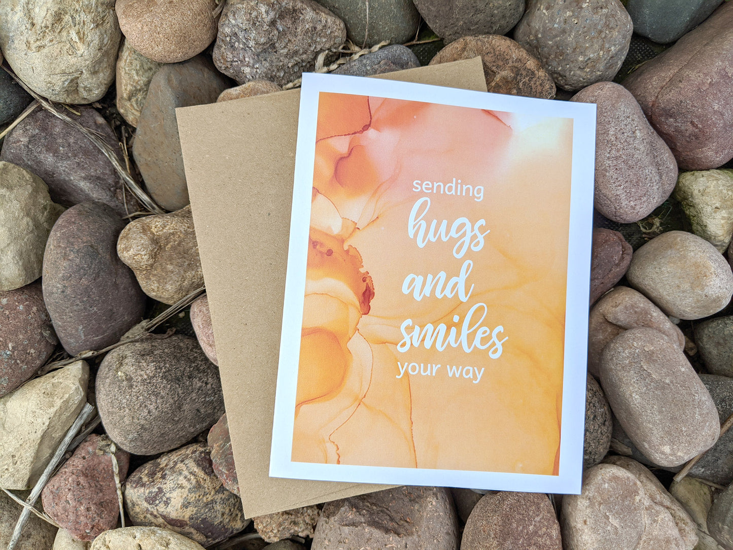 View from above of greeting card with kraft envelope on riverstones.