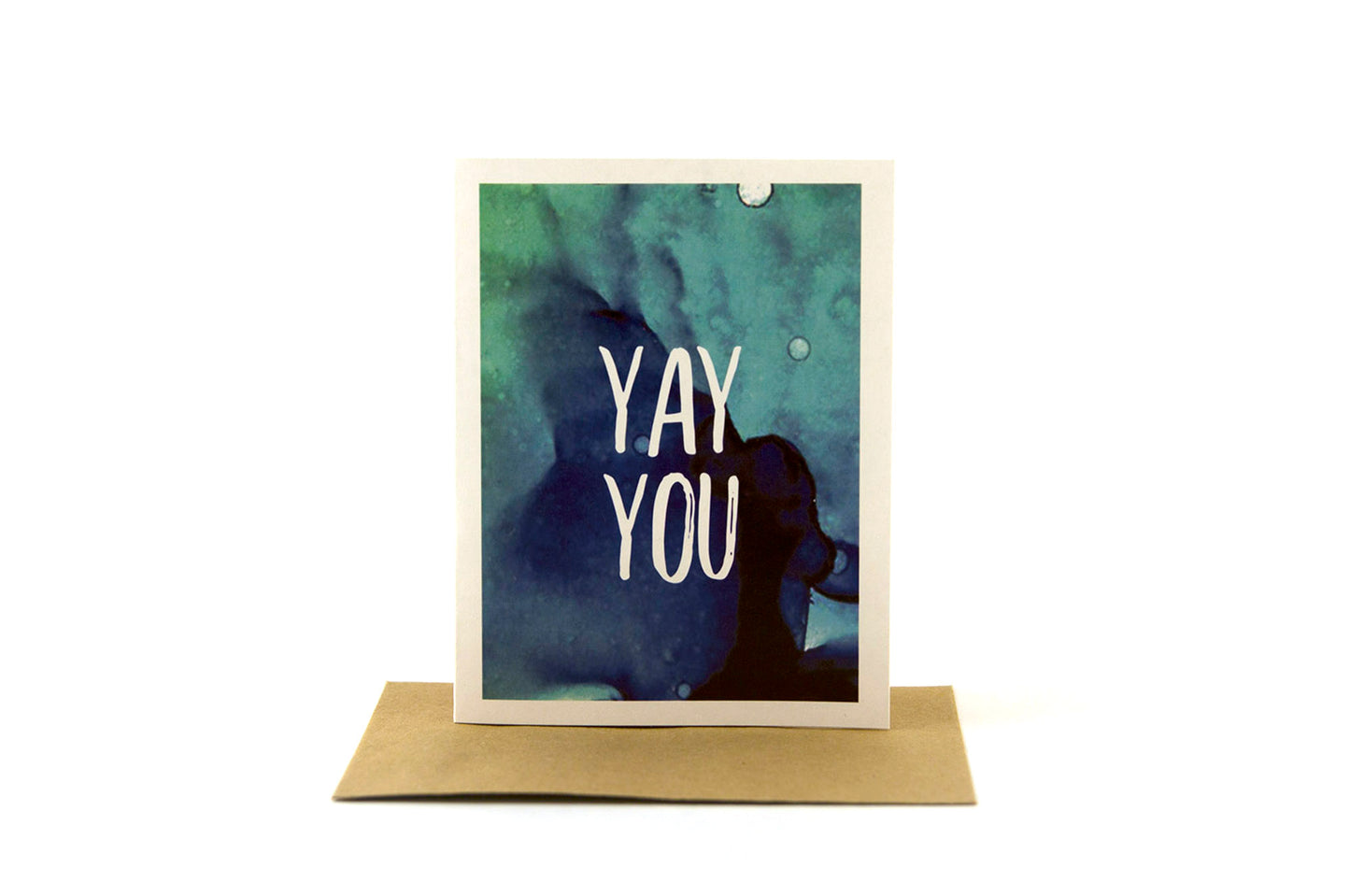 Greeting card standing upright on top of a kraft envelope against a white background.