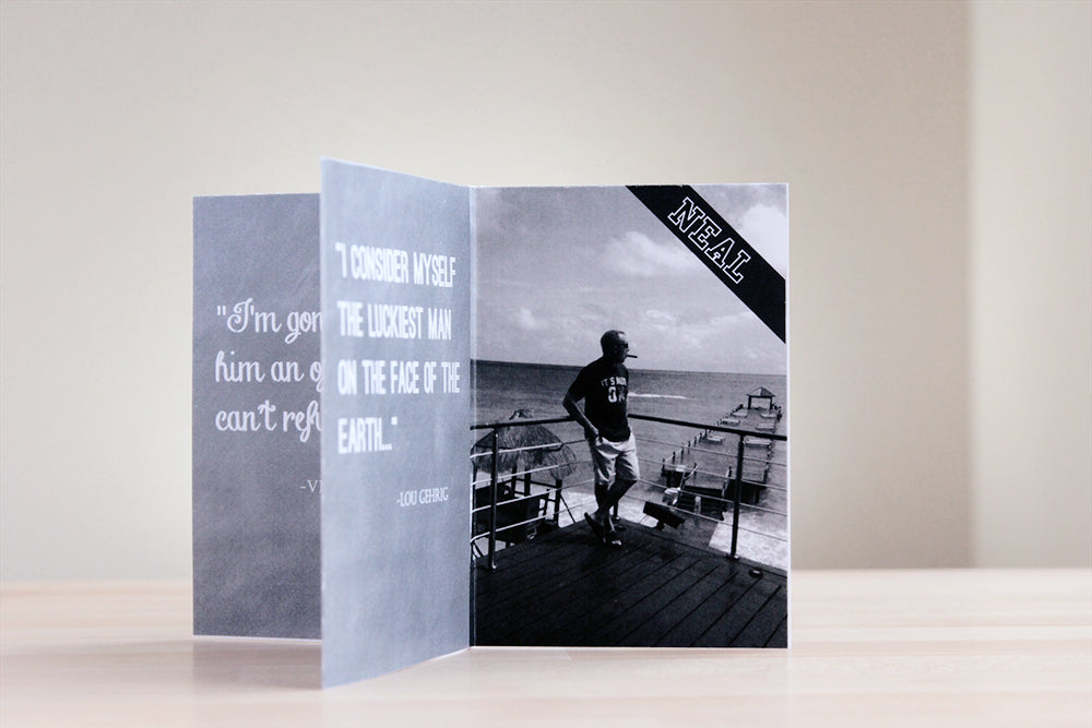Centerpiece sitting on a wooden table with a neutral wall in the background. The chalkboard texture of the panels includes favorite quotes and the photo is of a person standing against the railing of a deck in the tropics.