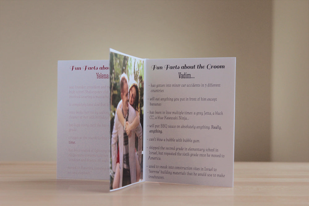 Centerpiece sitting on a wooden table with a neutral wall in the background. The panels show fun facts about the bride and about the groom along with an engagement picture of a piggy back ride in the forest.